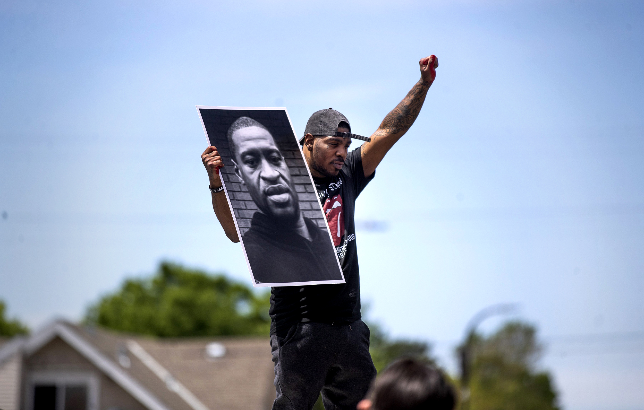 Tony L. Clark holds a photo of George Floyd outside the Cup Food convenience store, Thursday, May 28, 2020, in Minneapolis. (Jerry Holt/Star Tribune via AP) - Black Love Here’s Why Black Joy is an Act of Resistance
