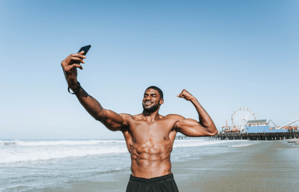 Courtesy of rawpixel.com - Black Love Man on the beach looking at phone