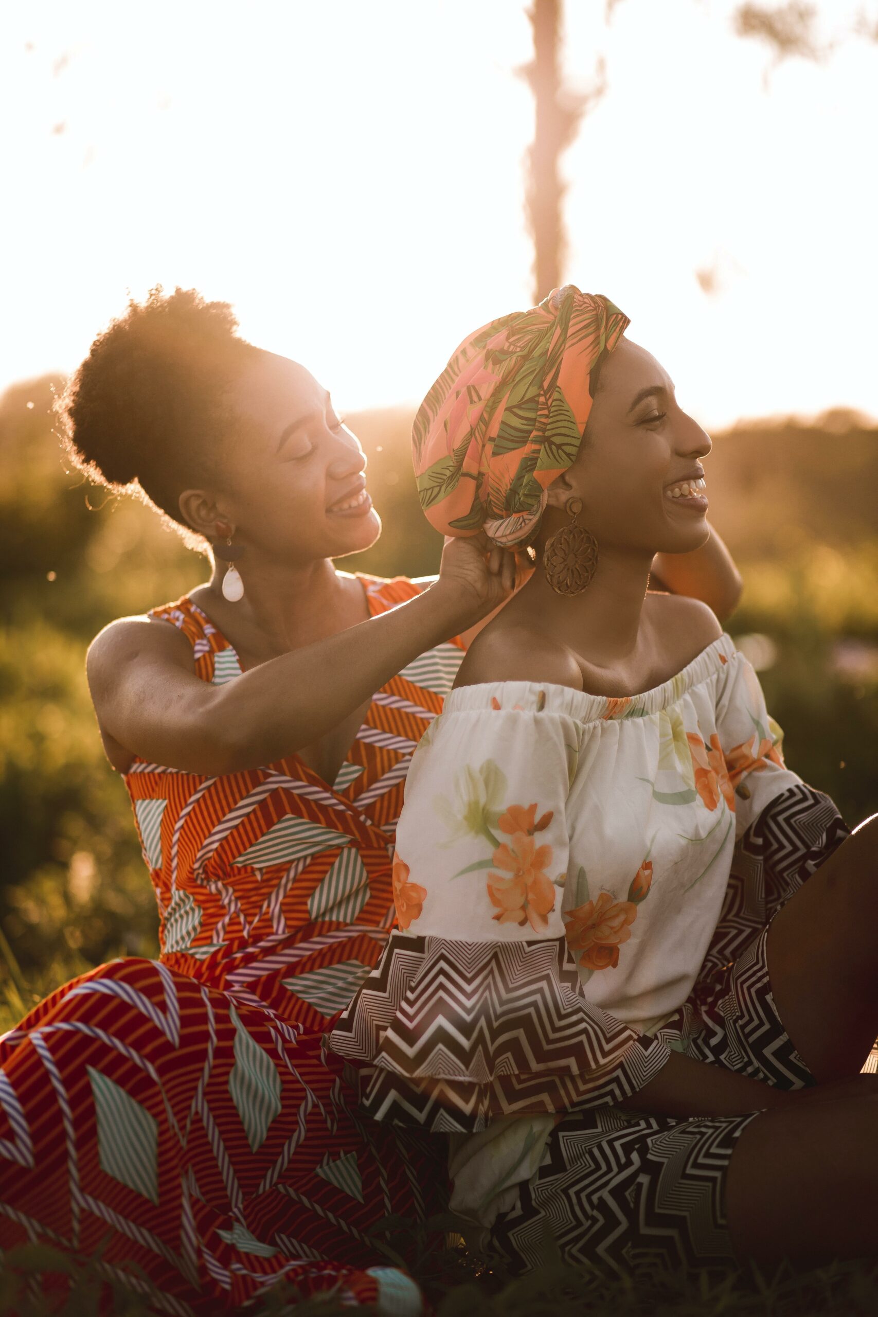 A woman helping her friend with her head wrap (Credit: Unsplash)