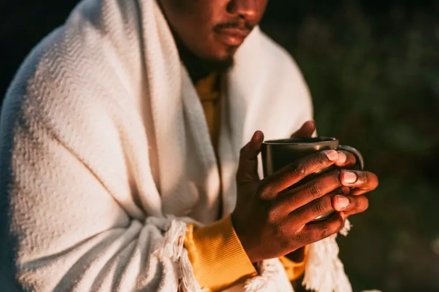 Man with a blanket on drinking a warm beverage