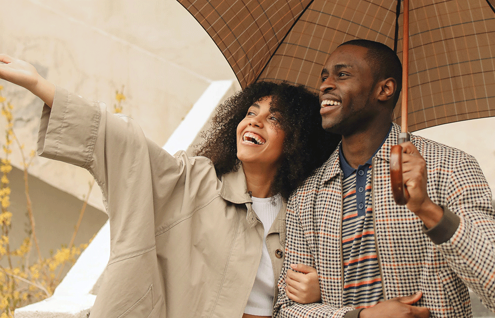 - Black Love couple smiling holding an umbrella