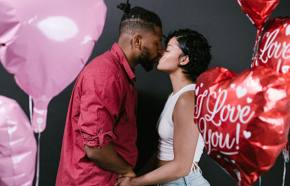 Courtesy of pexels.com - Black Love couple kissing surrounded by balloons