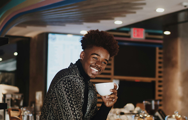 man smiling while drinking coffee